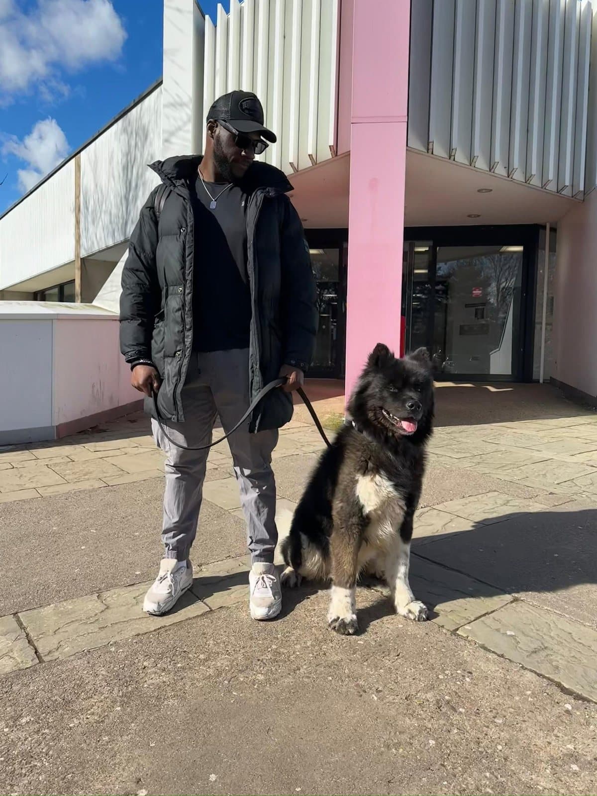 Dami standing with Atlas on a loose lead outside a station, both looking at the camera